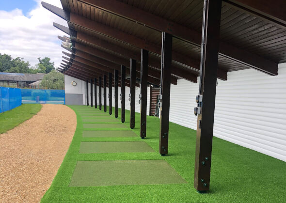 Naperville Covered outdoor tee line with light green synthetic grass boxes inside a dark green synthetic grass strip